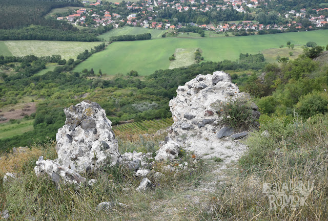 Csekély falmaradványok és hegy lábánál a falu