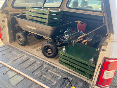 A black cart sits in the back of a truck full of tools for marsh fieldwork