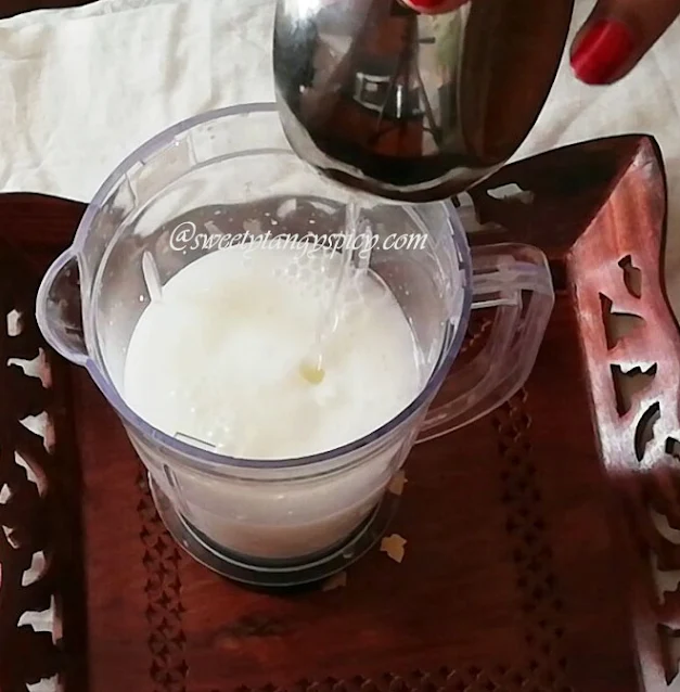 "Mixing rose water into the lassi mixture."