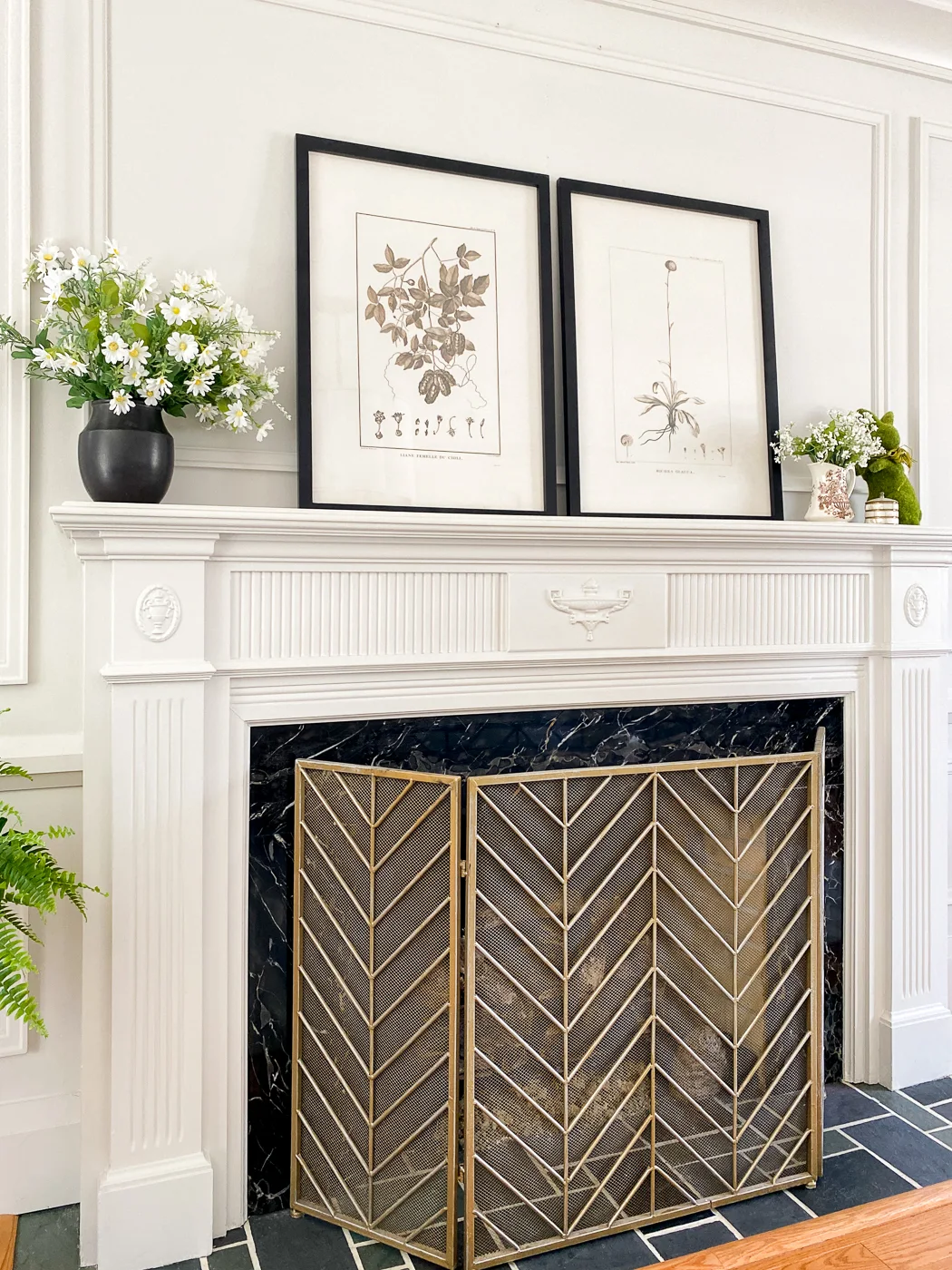 fireplace mantel with fireplace screen and botanical artwork