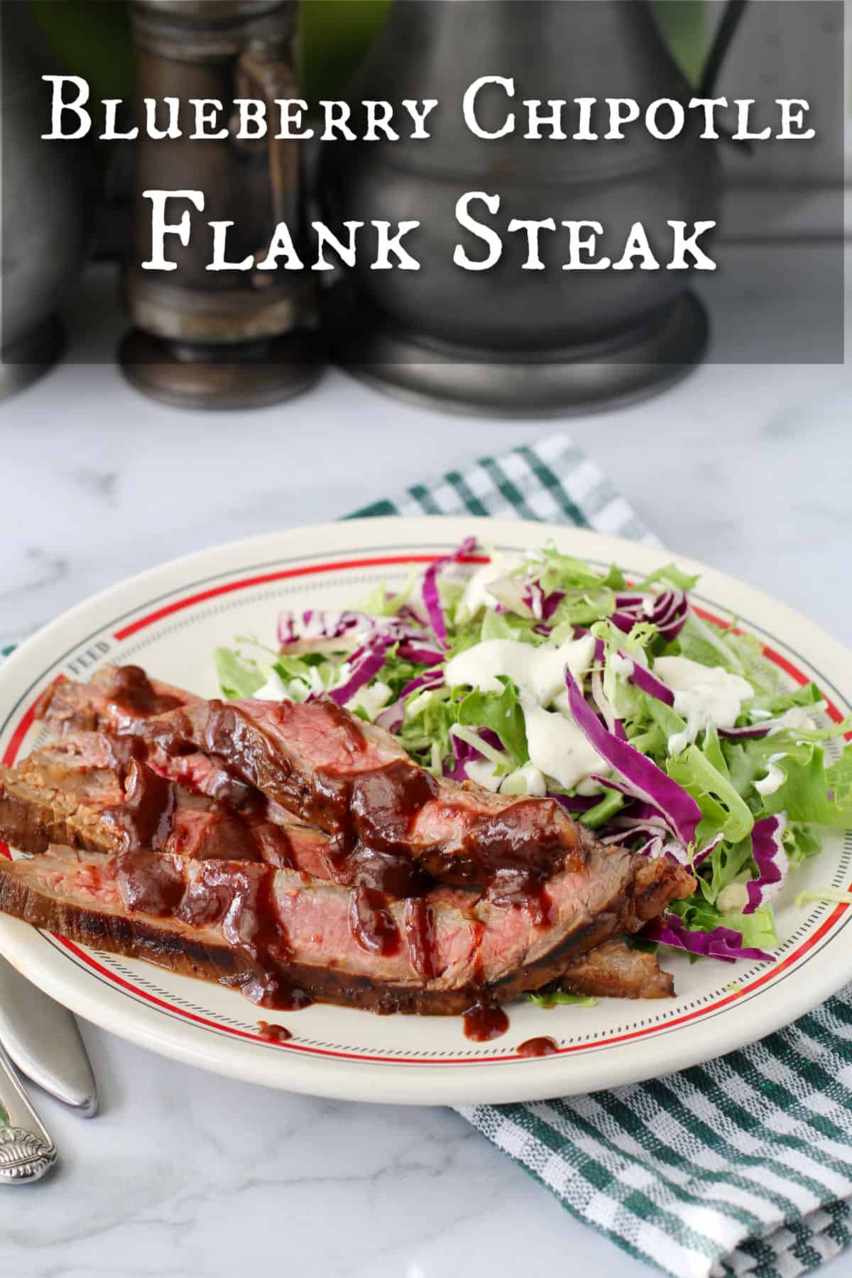 Blueberry Chipotle Grilled Flank Steak on a plate with a salad.