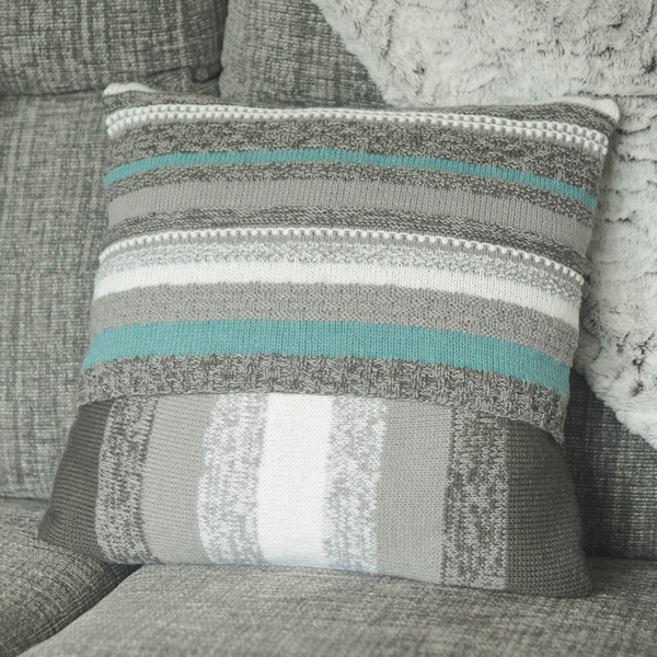 back of blue and grey knitted cushion on a grey sofa