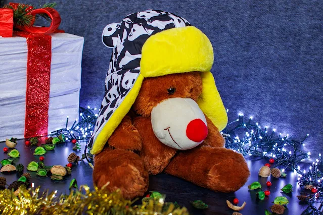 A cuddly reindeer wearing a child's hat with black and white panda hat, ears and yellow fleece lining