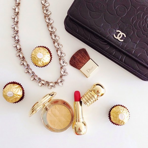 flat lay featuring rhinestone necklace, Chanel camellia-embossed wallet on chain WOC, Ferrero Rocher chocolates, Dior makeup