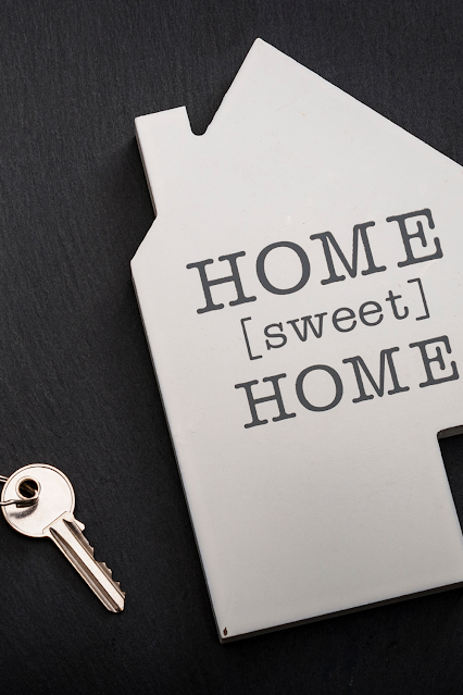 Photo of a white cardboard house, with an oldfashioned key beside it.