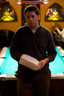 man in front of pool table with a bag of popcorn