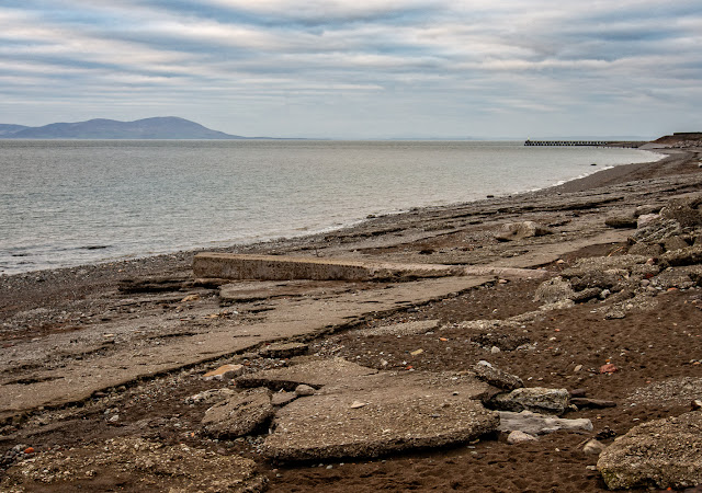 Photo of another view along the shore towards the pier with the Scottish hills in the distance