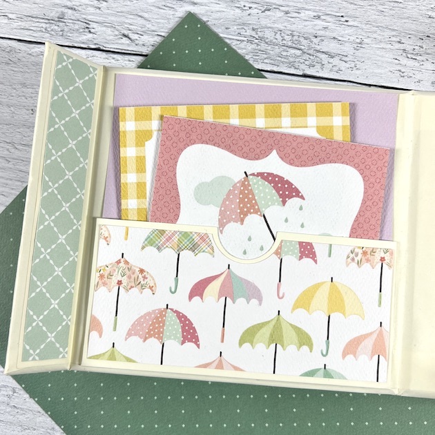 Beautiful spring scrapbook album page with umbrellas, a pocket, and journaling cards