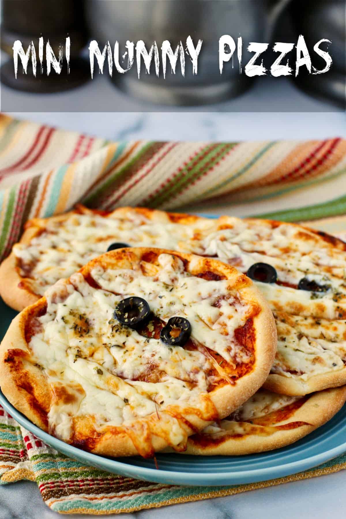 Mini Mummy Pizzas on a plate with olive eyes.