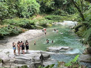 Turistas y familias disfrutan de las refrescantes piscinas naturales en la Laguna Azul, ubicada en el Talag, Tena, creando recuerdos felices en un entorno tropical.