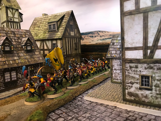 A patrol of halberdiers is led by a witch hunter.