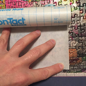 Process of applying contact paper to the surface of a large puzzle