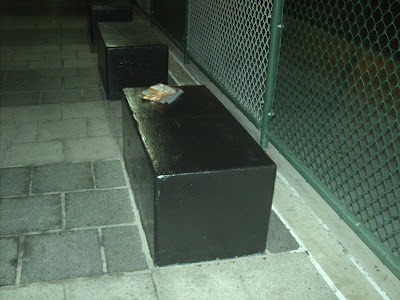 This is a close up of two white bread sandwiches on a black cement bench