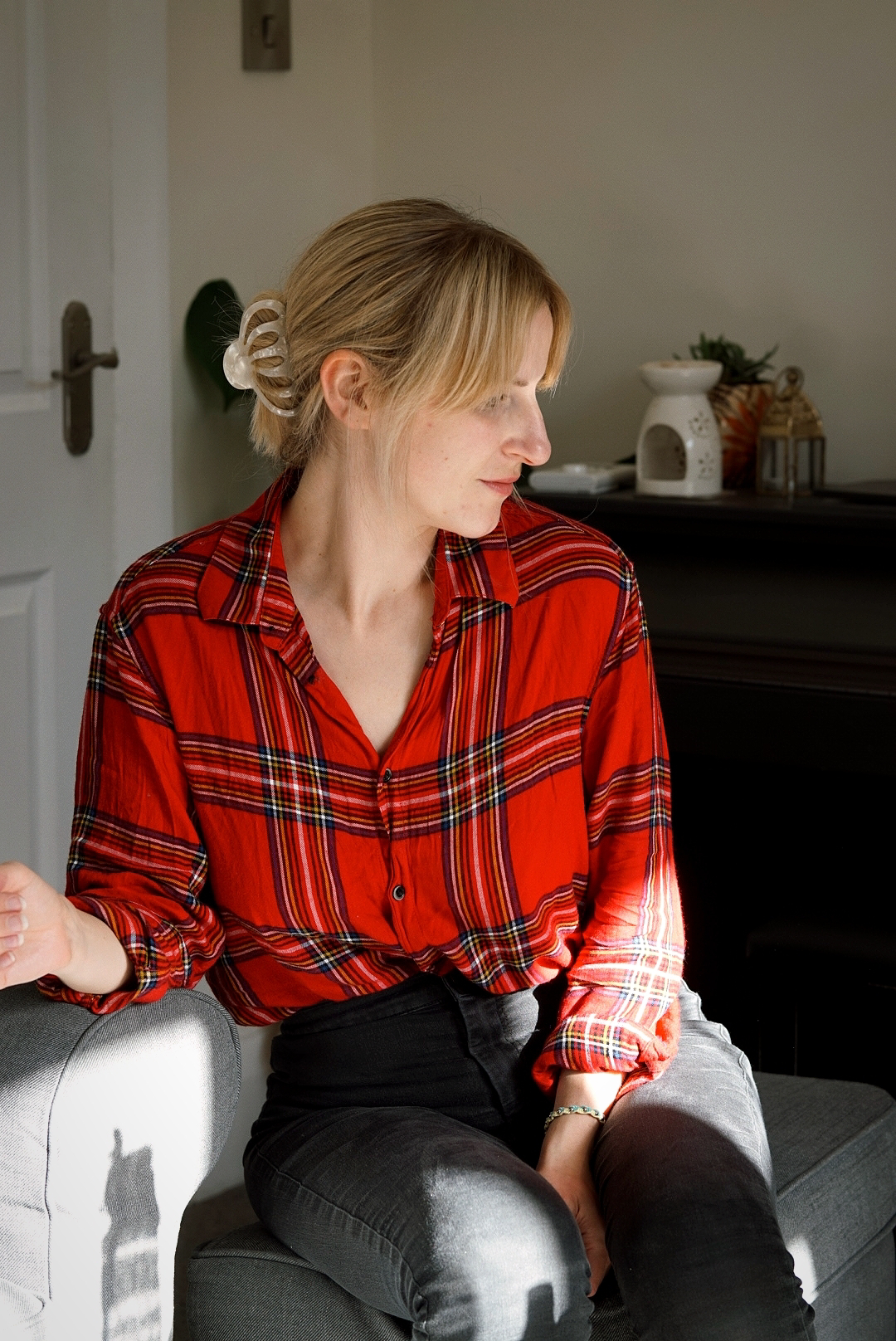 Amy is sitting down wearing a red tartan shirt tucked into black denim skinny jeans.