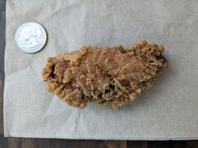 KFC Hot & Spicy Wing with quarter for size comparison.