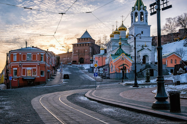 Дорога между старыми домами и церковью, а в отдалении башня кремля