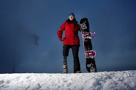 picture of michelle in snow with her snowboard. She is a right leg amputee and is wearing a prostetic leg. 