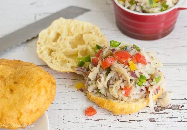 Saltfish buljol on top of fry bake on a white background.