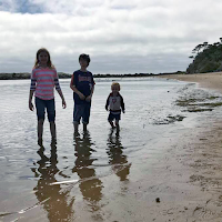  three kids wading in the water at the beach