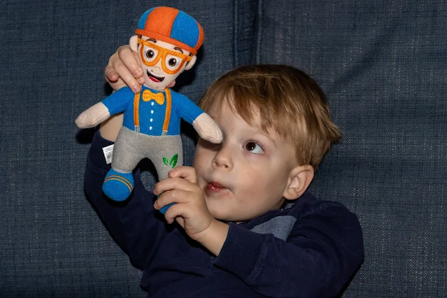 Playing with a blippi soft toy on the sofa