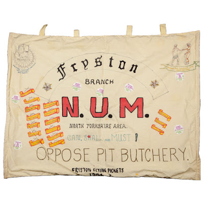 A large fabric hand stitched and drawn banner. Large text:Fryston Branch, N. U. M, Can, shall and must! Oppose Pit Butchery.