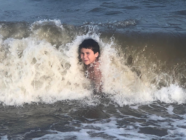 crashing wave on boy in the bay