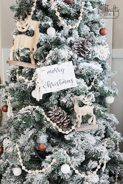 Neutral Christmas living room decor. Wood and white Christmas decor. Boho style Christmas decor. Bohemian style Christmas tree. Beaded and macrame Christmas tree decor and decorating ideas. How to decorate a Christmas tree. Farmhouse style Christmas decor. Wood and White Christmas mantel decor. Vintage Christmas mantel ideas. Flocked Christmas trees. Two story living room design.