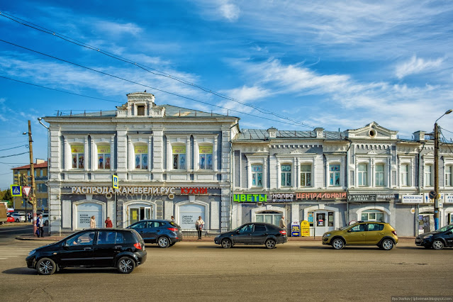 Машины на дороге у старого, ажурного двухэтажного здания