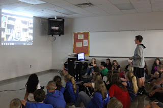 Students sitting on the floor watching Skype video of Henry Fenichel, a Holocaust survivor