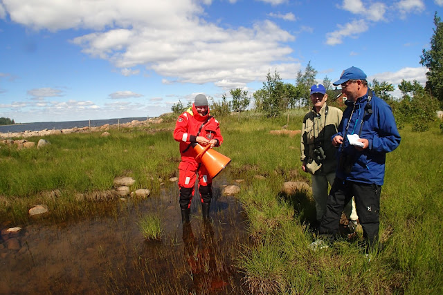 Meribiologi opastaa kahta miestä vesikiikarin käytössä.