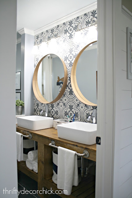 bathroom reno with tile wall and round mirrors