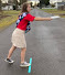 Young woman standing on a line and holding a paper plate and preparing to throw it like a discus.