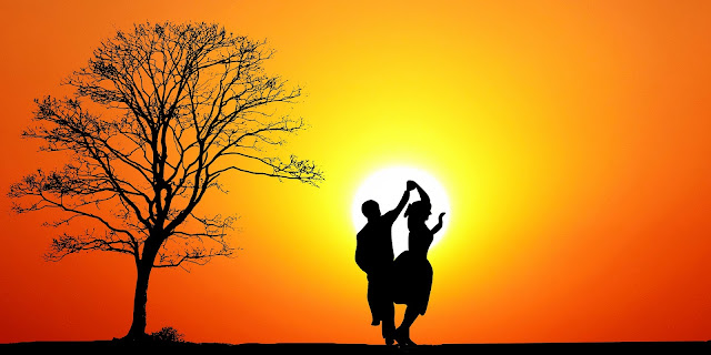couple dancing together at sunset under a tree
