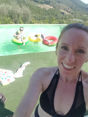 A woman stands in front of a family in bright coloured floaties in a pool