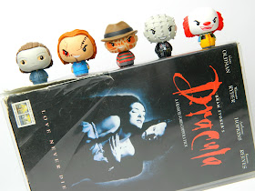 A photo showing a VHS tape of the horror movie Dracula, with horror character figures sitting on top