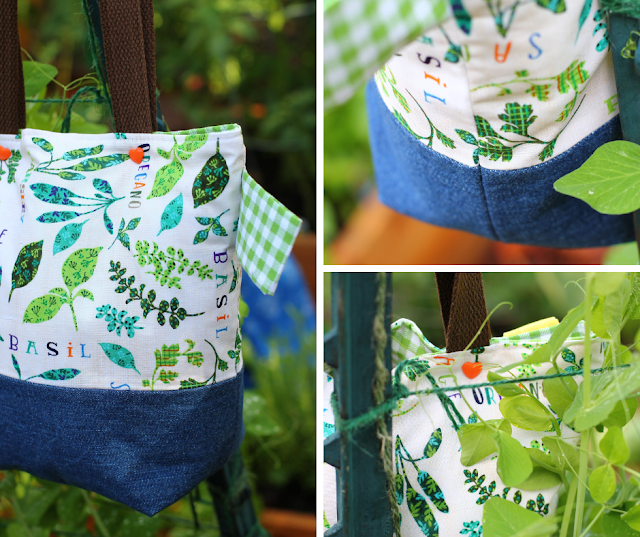 Three image collage of a herb garden patterned project bag with a denim boxed bottom and brown cotton webbing dual shoulder straps. Two orange heart snap buttons on top for closure. Green gingham side loop. Images of whole bag, close-up of perfectly lined up side seams, and button. Setting in a green thriving garden.