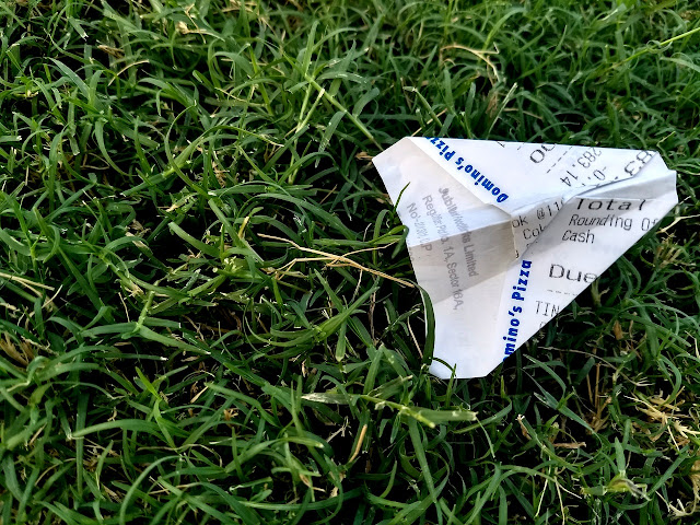 Tiny paper airplane in the grass