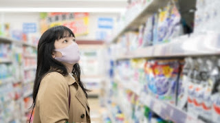 かかとが脱げるため応急処置グッズを買いにコンビニで買い物をする女性の写真