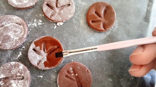 Homemade Chocolate Fondant dinosaur footprint decorations being brushed with a decorators brush