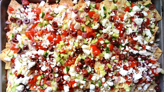 Mediterranean Nachos topped with cucumber, tomato, red onion, feta, kalmatas