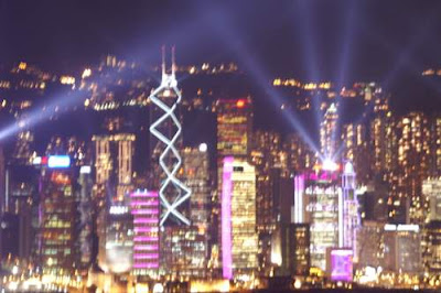 A blurred image of Hong Kong Island's skyline, lit up at night.