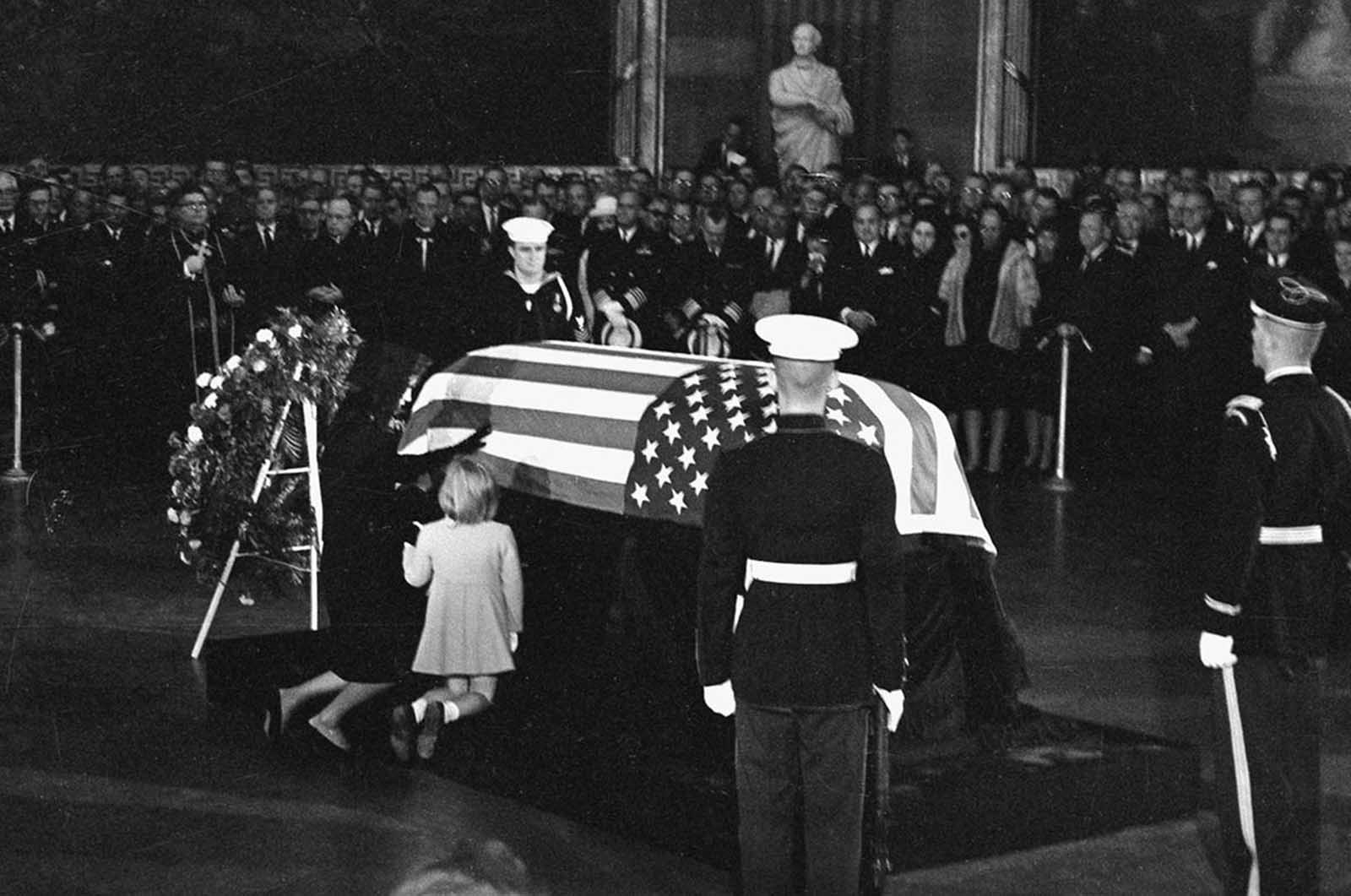 Widow Jacqueline Kennedy kneels and reaches out to touch the casket of her slain husband, John F. Kennedy, in the rotunda of the Capitol in Washington, District of Columbia, on November 24, 1963. Their daughter Caroline kneels beside her.