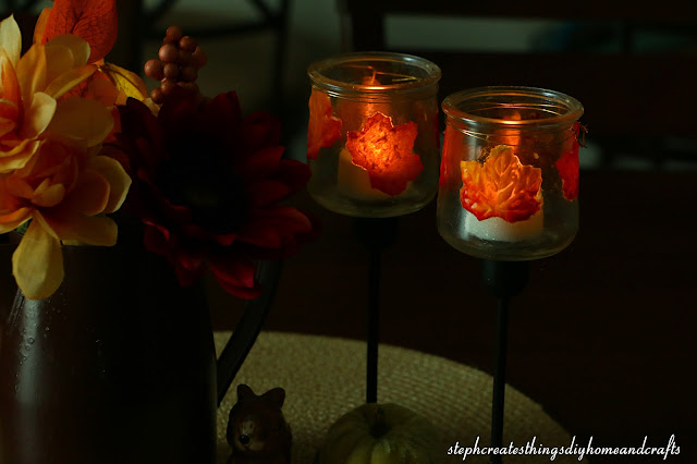 Completed glass candle jars displayed with tealight candles near fall floral