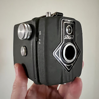 Hand die een groene Dacora Daci-boxcamera opsteekt