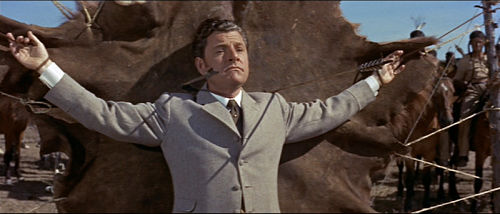 Kenneth More tied up with arrows being fired at him