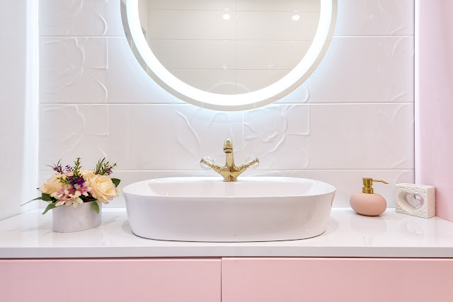 A pink and whited-themed vanity area in the bathroom, featuring a mirror with LED back lighting.