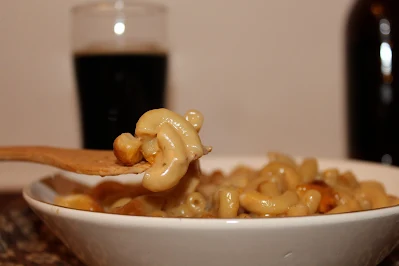 Bowl of stout macaroni and cheese with a fork picking up a bite.