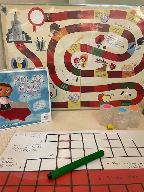 Na stoliku leży krzyżówka w biało-czerwonych barwach, gra "Polak mały" oraz wiedzowa gra planszowa na temat Polski.