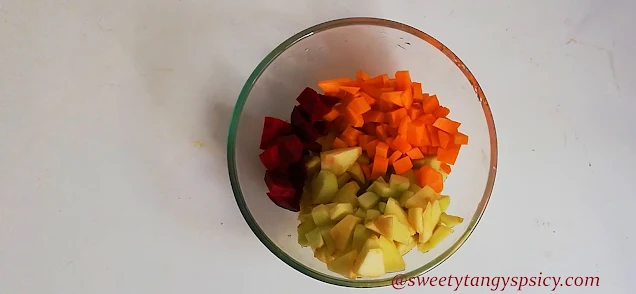 "Fresh carrots, apples, and beetroots neatly arranged on a cutting board, ready for preparation