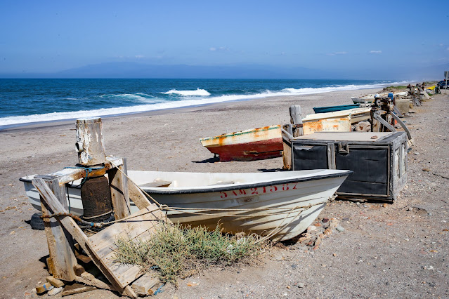 Pequeñas barcas de madera sobre la arena de la playa amarradas con las azules aguas del mar al fondo